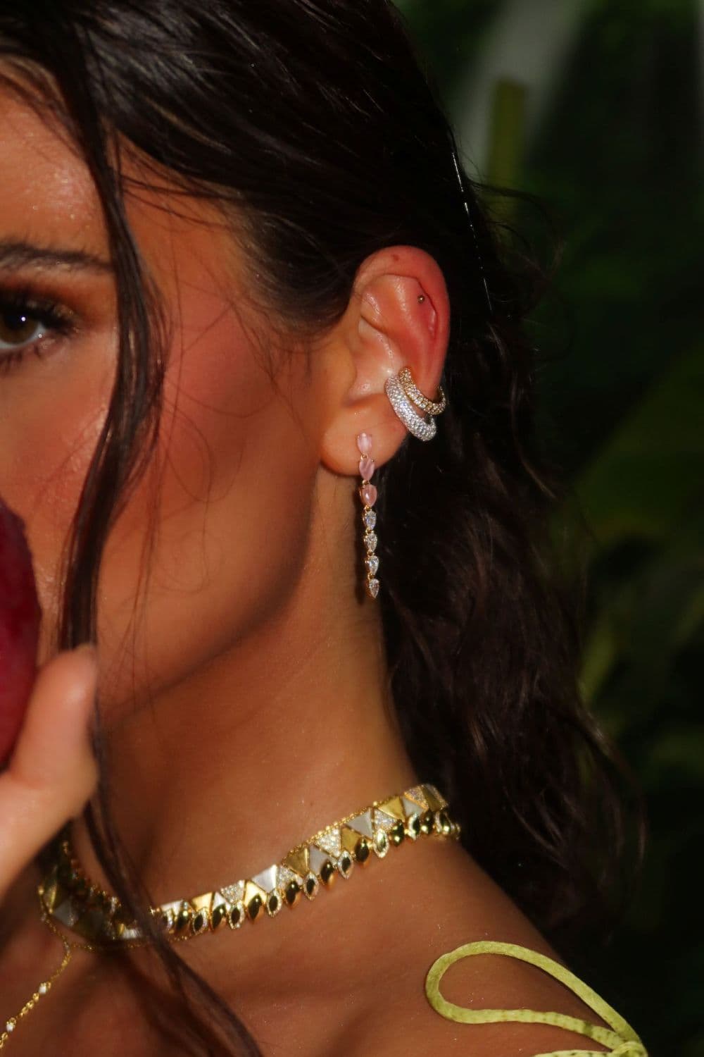 Close-up of a person wearing gold earrings and a gold necklace