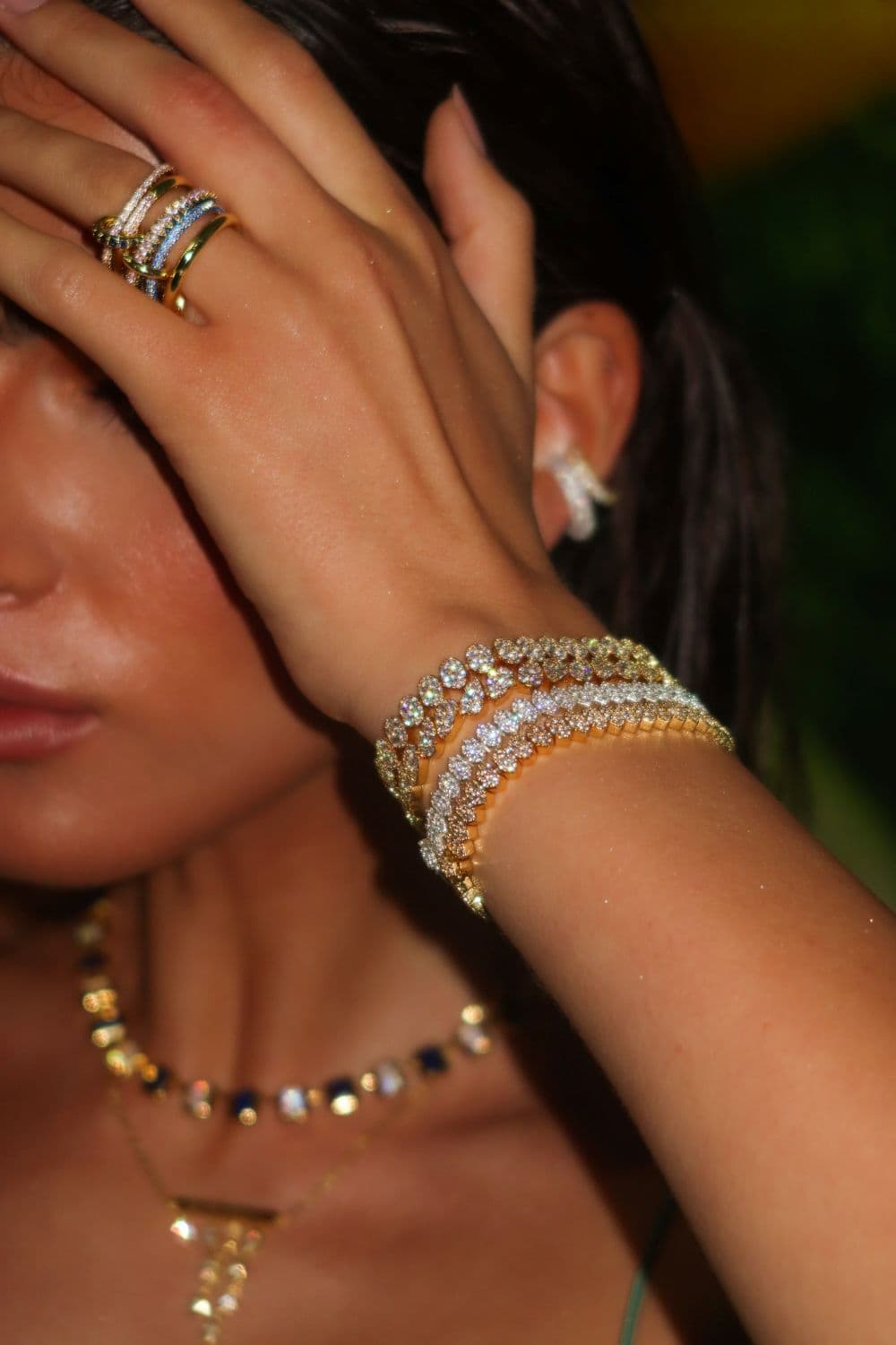 Close-up of a hand wearing multiple jewelry pieces.