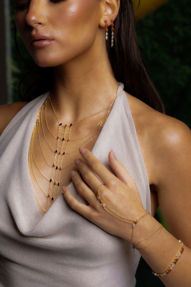 Woman wearing a beige dress with a necklace and earrings.