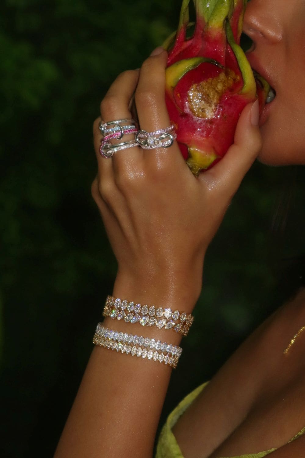 Person holding a dragon fruit with jewelry on a dark background
